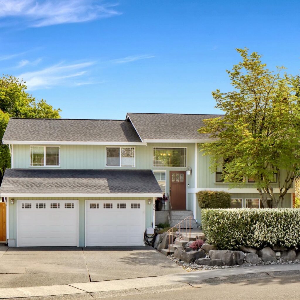 Two story home with a double garage and trees in the front yard.