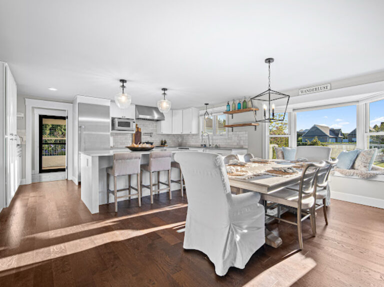 Bright furnished kitchen and dining area with white cabinetry and wood floors.