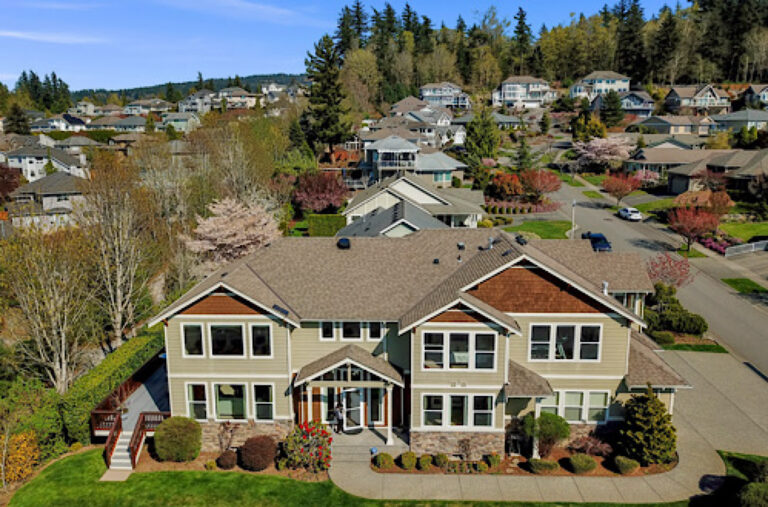 Large home seen from above, surrounded by a residential neighborhood and trees.