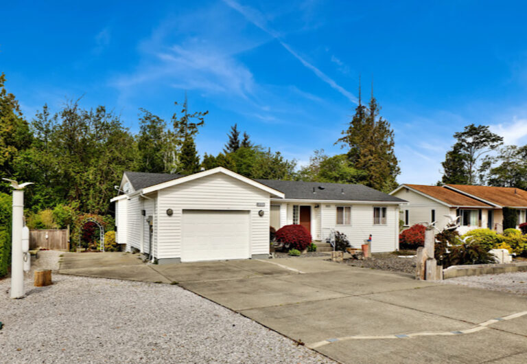 Single story home with a garage, driveway and mature landscaping.